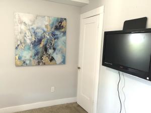a flat screen tv on a wall with a painting at Pasadena Room with private bathroom in Pasadena