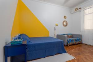 Un dormitorio con una cama azul y una pared amarilla. en Cafofo Nice, en Río de Janeiro