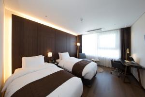 una camera d'albergo con tre letti e una scrivania di Ramada by Wyndham Daejeon a Daejeon Altre 28 foto