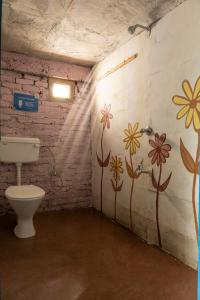 a bathroom with a toilet and flowers painted on the wall at Vista Hostel Jeolikote, Nainital in Patwa Dunga