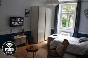 聖克洛德的住宿－Charmant Studio au calme à 5 min du centre ville，一间卧室设有一张床、一台电视和一个窗口。