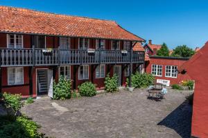a red house with a courtyard in front of it at Pension Sandbogaard in Sandvig