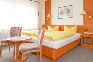 a bedroom with a bed and a table and a chair at Hotel Pension Loose in Borkum