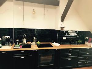 une cuisine avec des armoires noires et un comptoir dans l'établissement Helle Dachgeschosswohnung für 8 Personen in zentraler Lage, à Berlin