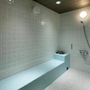 a bathroom with a bath tub with blue tiles at Candeo Hotels Osaka Kishibe in Suita