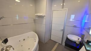 ein weißes Badezimmer mit Badewanne und Waschbecken in der Unterkunft צימר גראפה בערבה - Grappa in Yahel