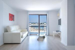 a white living room with a couch and a table at Jacaranda Apartments & Studios in Es Cana
