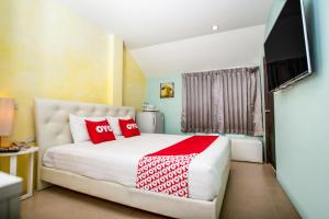 a bedroom with a large bed with red pillows at OYO 345 The Click Guesthouse At Chalong in Rawai Beach