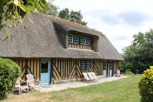 a thatch roofed house with chairs and a porch at La Chaumière aux Faisans in Ablon