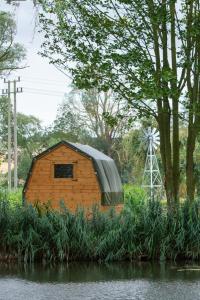 a small building with a roof on the side of a river at The Moat Lake Glamping Pod in Clare