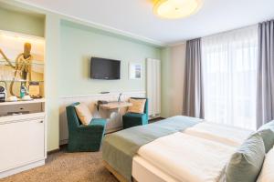 um quarto de hotel com uma cama, uma secretária e uma televisão em Hotel Regina Maris em Norddeich