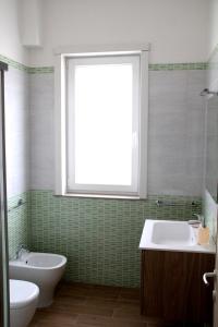 baño con bañera, lavabo y ventana en Altomare Case Vacanza, en Torre Lapillo