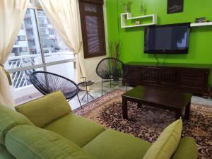 a green living room with a couch and a tv at Rose Condo@ Cocobay Beach Resort in Port Dickson