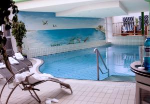 um mural de piscina numa casa de banho com uma cadeira em Hotel Regina Maris em Norddeich