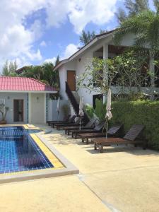 een resort met een zwembad, ligstoelen en een huis bij Pratum Resort in Khao Lak