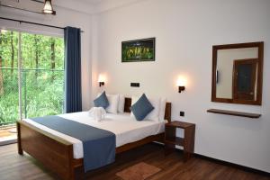 a bedroom with a bed with a mirror and a window at Forest Edge Safari Villa in Udawalawe