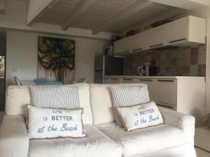 Biała kanapa z dwoma poduszkami mówiąca, że życie jest lepsze na plaży w obiekcie Casa Maia with shared swimming pool w mieście Palau