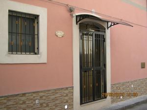różowy budynek z czarnymi drzwiami i zegarem w obiekcie Sicily Sun w mieście Lentini