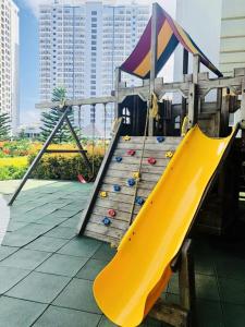 eine gelbe Rutsche auf einem Spielplatz mit Gebäuden im Hintergrund in der Unterkunft Heaven Suites, Tagaytay Condominium, Wind Residences in Tagaytay