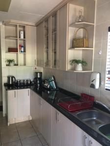 a kitchen with white cabinets and a black counter top at Villa Danamara in Phalaborwa