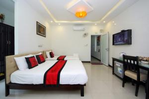 een slaapkamer met een bed en een televisie. bij Flame Flowers Homestay in Hội An