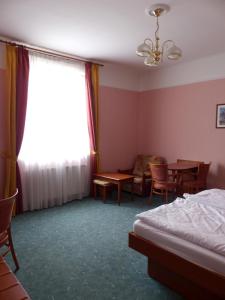 a bedroom with a bed and a table and a window at Penzion Harmonie in Chodov
