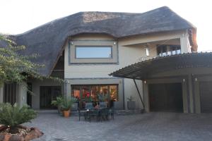 una casa con techo de paja, mesas y sillas en Oryx B&B Reserved Guests Only, en Mokopane