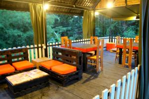a porch with a table and chairs on a deck at hornbill river cottage udawalwa in Udawalawe