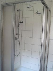 a shower in a bathroom with white tile at Ländliche 1-Raumwohnung im Park in Thulendorf