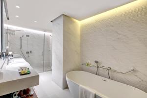a bathroom with a tub and a sink and a shower at Millennium Place Barsha Heights Hotel in Dubai