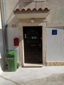 drzwi do budynku z koszem na śmieci przed nim w obiekcie Guest House Accommodation Rupine w mieście Premantura