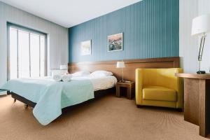 ein Schlafzimmer mit einem Bett und einem gelben Stuhl in der Unterkunft Hotel Willowa in Lublin