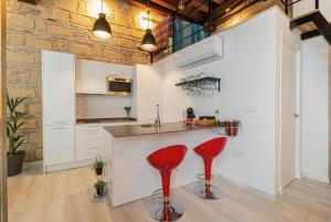 uma cozinha com armários brancos e bancos vermelhos em Loft en casco histórico La Pintora - Parking publico opcional em Jerez de la Frontera