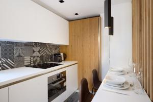 uma cozinha com armários brancos e uma mesa com cadeiras em Lou Cassiden - Magnifique appartement sur le Port em Cassis