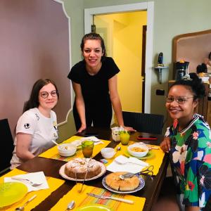 un grupo de tres mujeres sentadas en una mesa con comida en Charming Rooms Opuntia en Carloforte