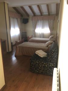 ein Schlafzimmer mit 2 Betten und einem Sofa in einem Zimmer in der Unterkunft HOSTAL EL ESCUDO in Cilleruelo de Bezana