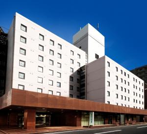 a large white building on the side of a street at Valie Hotel Hiroshima in Hiroshima