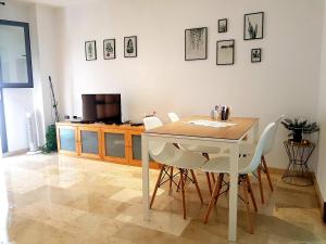 une table à manger avec des chaises blanches et une télévision dans l'établissement Bel appartement au centre ville et de la plage, à Ceuta