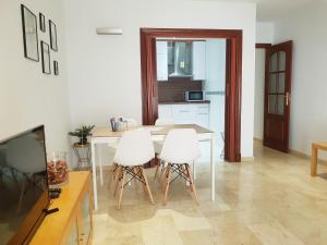 una cucina con tavolo e 3 sedie bianche di Bel appartement au centre ville et de la plage a Ceuta