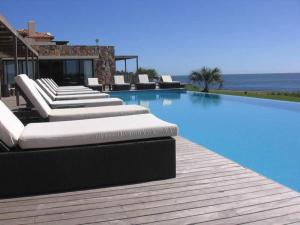 a swimming pool with chaise lounges on a wooden deck at Quartier Punta Ballena 2 dorm en suite in Punta del Este