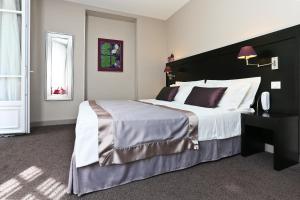a bedroom with a large bed with a black headboard at La Place Boutique Hotel in Antibes