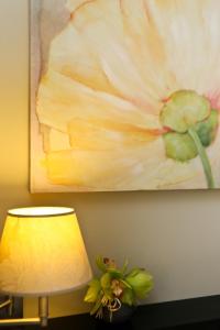 a painting of a flower on the wall next to a lamp at La Place Boutique Hotel in Antibes