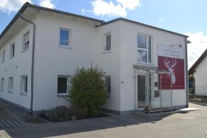 a white building with a sign on the side of it at Boardinghouse Gruber in Kranzberg