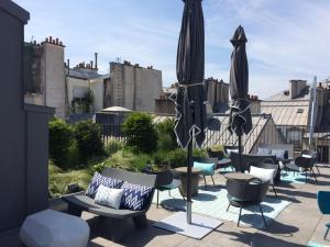 a patio with chairs and umbrellas on a roof at Drawing Hotel in Paris