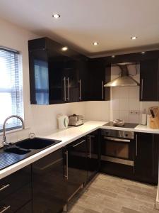 una cocina con armarios negros y fregadero en 2 Laurel Court en Ulverston