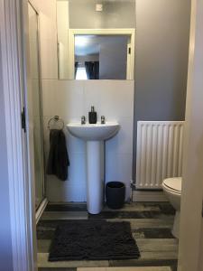 ein Badezimmer mit Waschbecken, Toilette und Spiegel in der Unterkunft Luxury Portrush Holiday Homes - The Green, Portrush Sleeps 12 - 5 bedrooms in Portrush + 42 Fotos