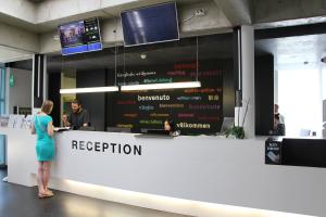 a woman standing in front of a reception desk at Geneva Hostel in Geneva
