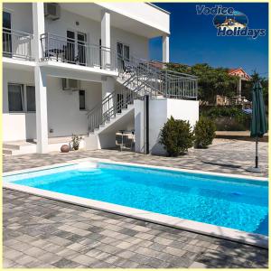 a swimming pool in front of a house at TayLa-Apartment Vodice in Vodice