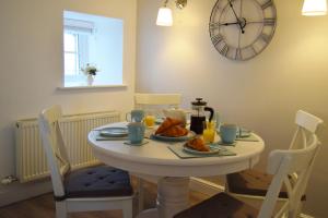 a white table with food and a clock on the wall at Number 10, Isle of Luing in Cullipool