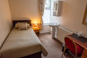 a small bedroom with a bed and a sink at Aarondale Guest House in Hartlepool